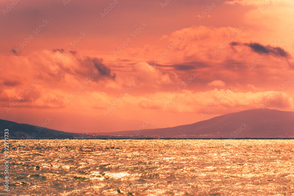 Azure sea, mountains, orange golden sky at sunset. Summer sea scenic landscape on sunny evening