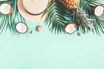 Summer composition. Tropical palm leaves, hat, coconut, pineapple on mint background. Summer concept. Flat lay, top view, copy space