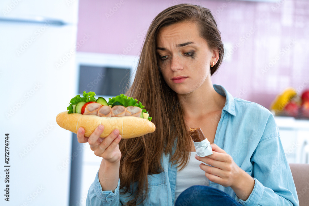 Sad, unhappy stressed woman eating unhealthy junk food and chocolate because of depression and stress. Nerve food. Life problems and difficulties. Food addiction Sad, unhappy stressed woman eating unhealthy junk food and chocolate because of depression and stress. Nerve food. Life problems and difficulties. Food addiction