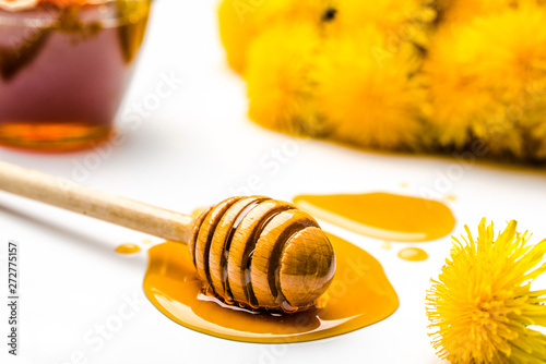 Dandelion honey - stick with drop of honey on white background