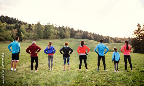 Rear view of large group of multi generation sport people standing in nature.