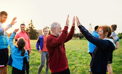 Large group of fit and active people resting after doing exercise in nature.