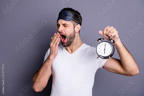 Portrait of his he nice-looking attractive tired bearded guy holding in hand clock waking up isolated over gray pastel violet purple background