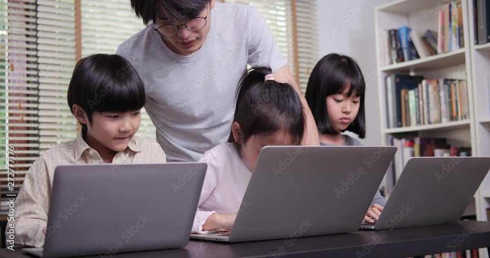 Group of student using laptop together at classroom. Teacher training children to use computer. Technology and Education concept.