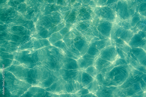 The sun pattern is a play of light and shadow in the form of highlights, spots and streaks on the calm clear surface of the emerald transparent sea water