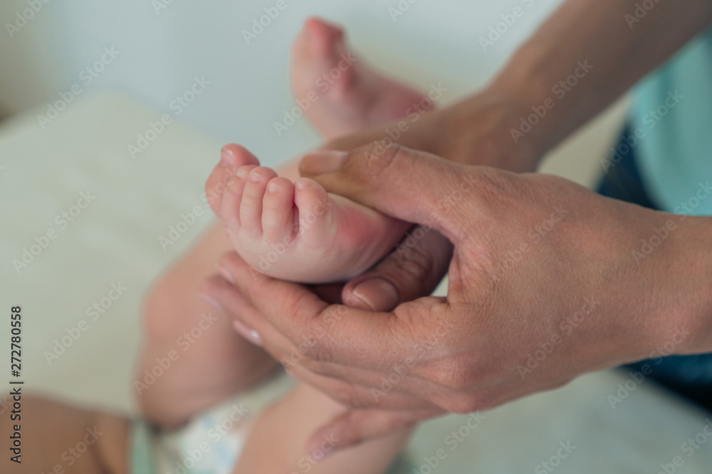 Close-up of a woman's hand holding a child's leg. Baby massage. Close-up of a woman's hand holding a child's leg. Baby massage.