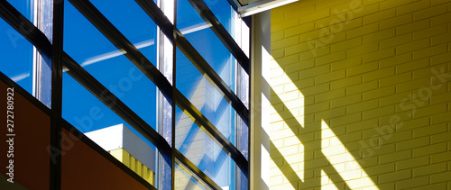 Fotografía Blue sky and sunlight through window with shadows of window frame on yellow wall