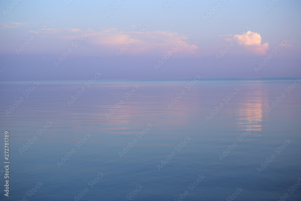 Fototapeta premium Background of seascape in sunset. Calm sea and purple sky with clouds. 