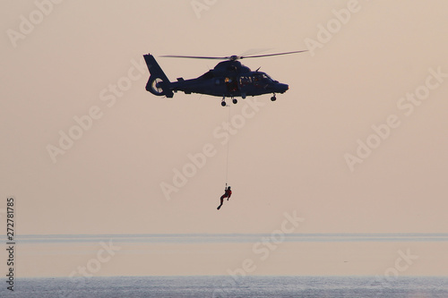 Rescue helicopter during an exercise. Rescue of the person at sea by helicopter.