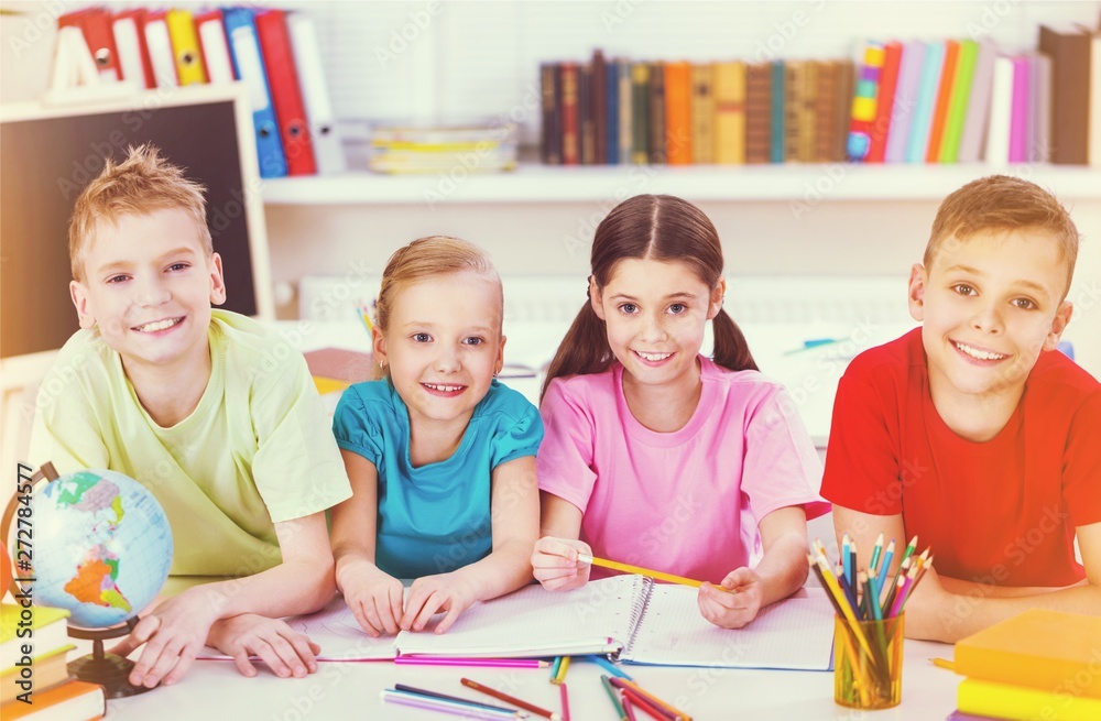 Fototapeta premium Friendly school children with books at class