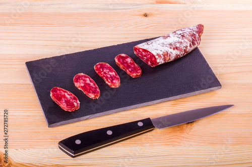 Spanish fuet, a dry sausage typical in Catalonia region, cut in slices on a wooden kitchen table photo