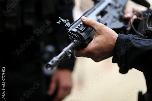 .Details with the hands of a man holding an automatic rifle. © MoiraM