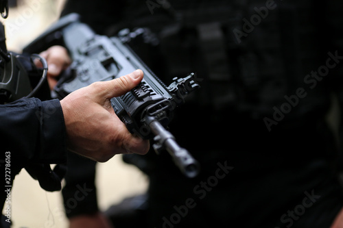 .Details with the hands of a man holding an automatic rifle.