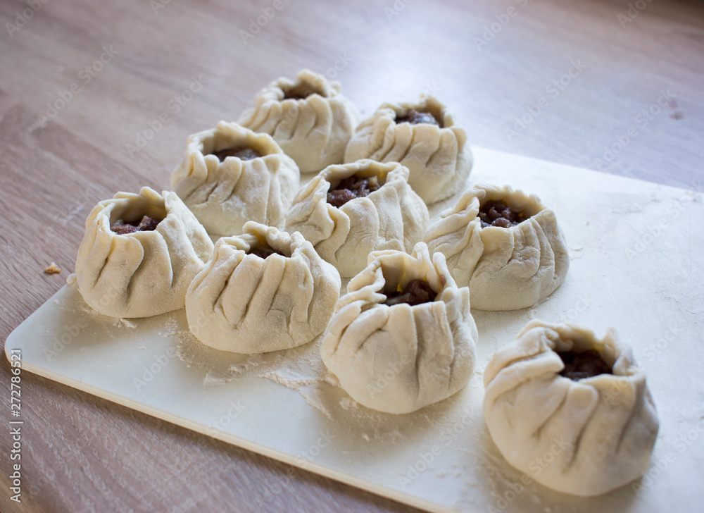 The process of making home-made dumplings. Raw homemade dumplings on a wooden board. Molding dumplings. The process of making home-made dumplings. Raw homemade dumplings on a wooden board. Molding dumplings.