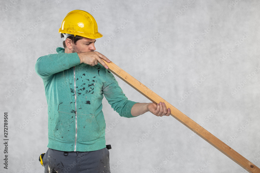 the construction worker holds a piece of board in his hands, the concept of choosing wood for construction the construction worker holds a piece of board in his hands, the concept of choosing wood for construction