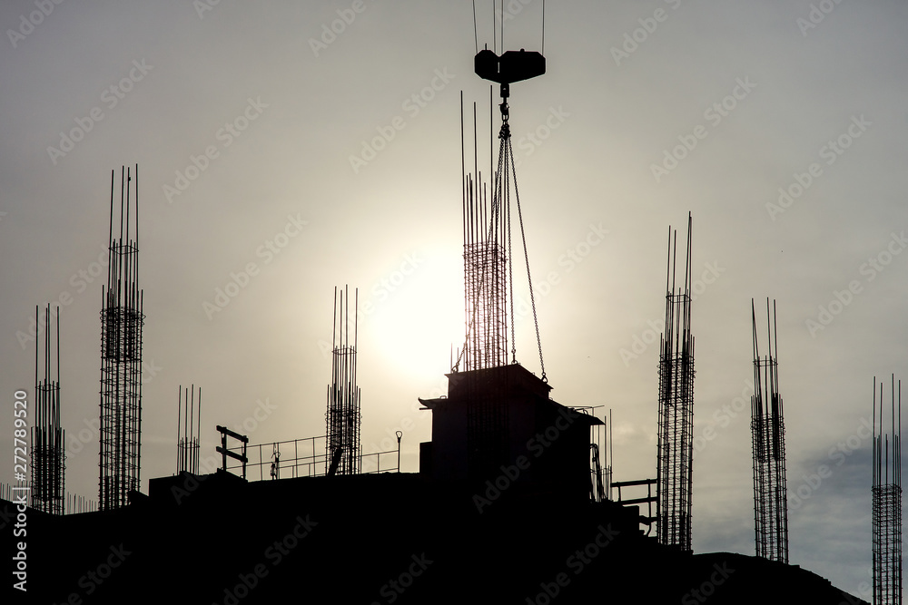 silhouette of a high-rise building under construction against the sun.