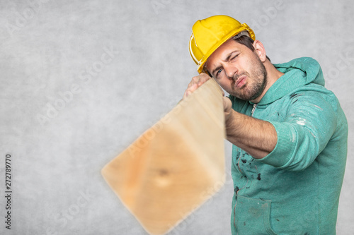 the construction worker holds a piece of board in his hands, the concept of choosing wood for construction photo