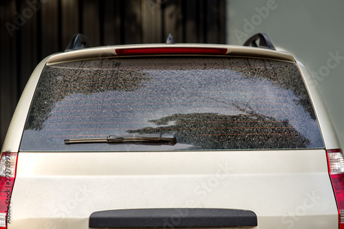 rear view of a dirty car, hatchback with a dusty trunk lid and a faulty car wiper.