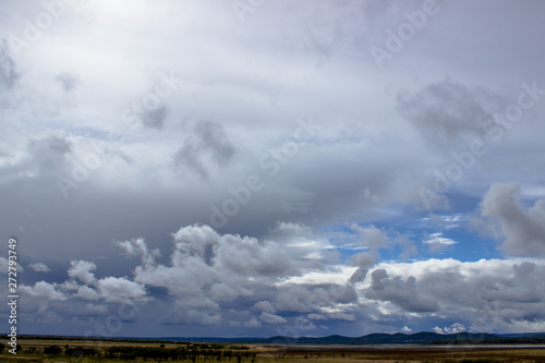 Cloudy blue sky on the horizon of Russian fields and mountains. Summer forest on a sunny day. © Вероника Одинокова