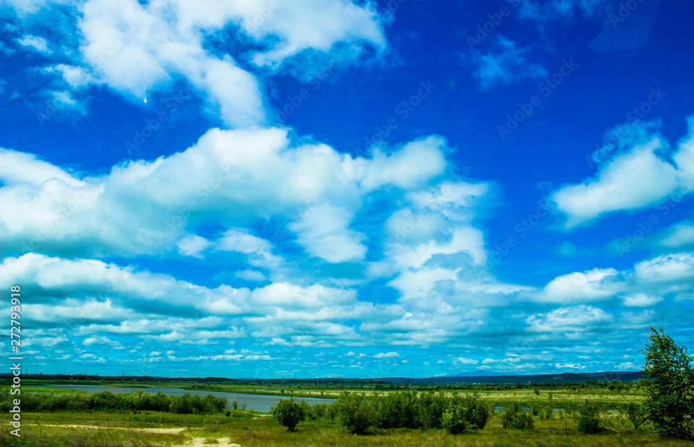 Cloudy blue sky on the horizon of Russian fields and mountains. Summer forest on a sunny day.