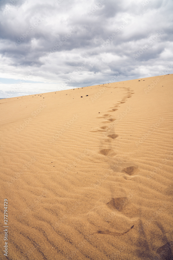 Footprints on the sand dunes. Mystical skies in the background.