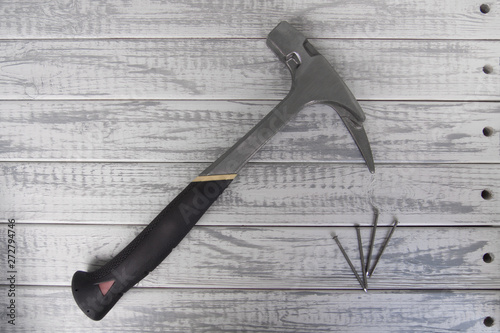 Hammer of carpenter or roofer and several nails on grey wooden background photo