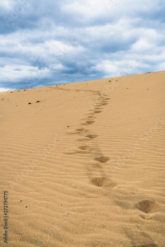 Footprints on the sand dunes. Mystical skies in the background.