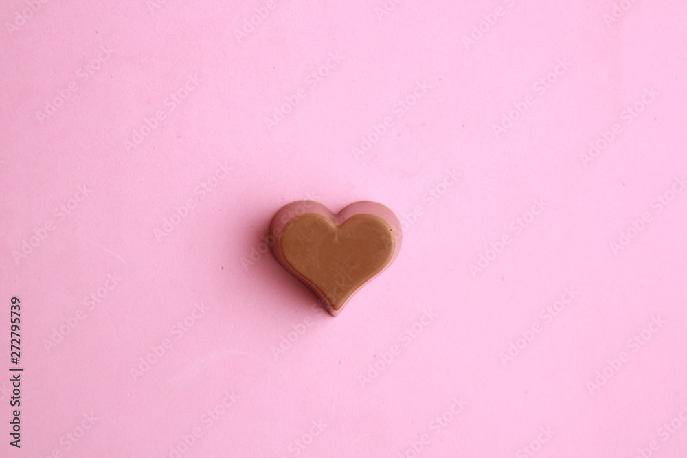 Chocolate bonbon with heart shape in color background