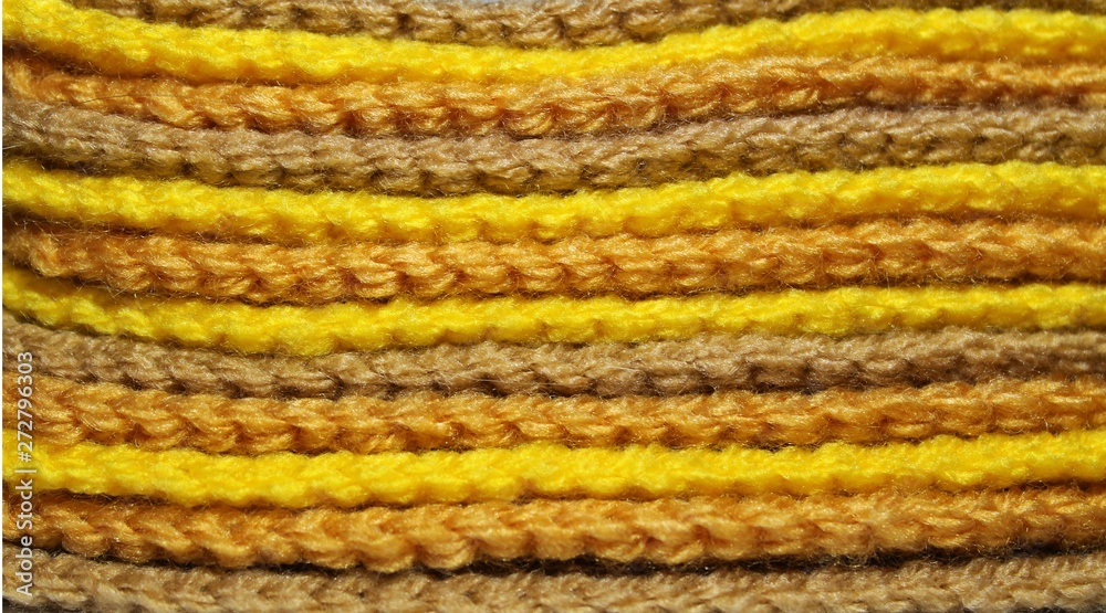 A pile of bright yellow and brown knitted elements. Warm and soft wallpaper, pattern, background