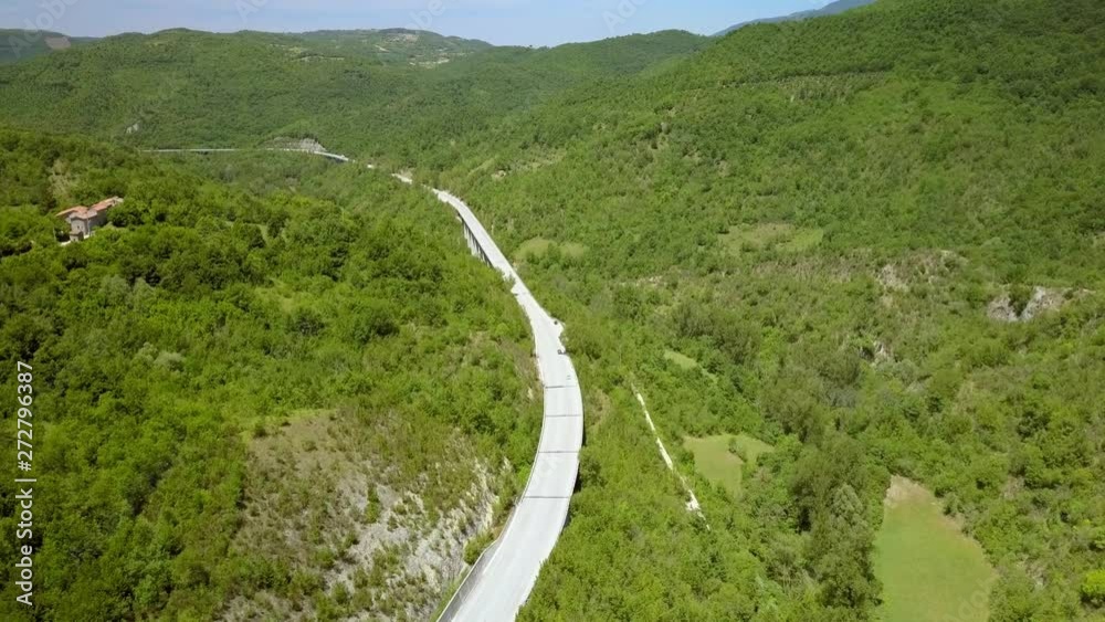 The aerial view of the road going up the mountains in Petrello Salto with the car running speedily on it The aerial view of the road going up the mountains in Petrello Salto with the car running speedily on it
