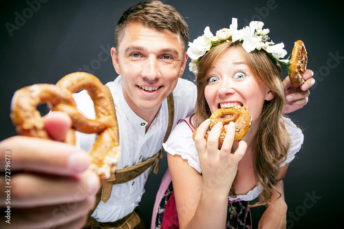 Two friends, man and woman, with pretzels in Bavarian traditional Oktoberfest clothes