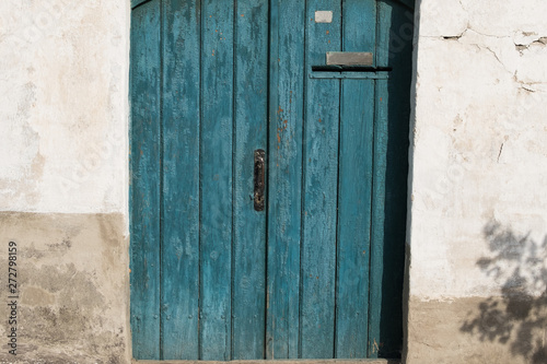 Old wooden door with handle, keyhole and post hole. Door with blue cracked paint. Wood texture. © Eugene