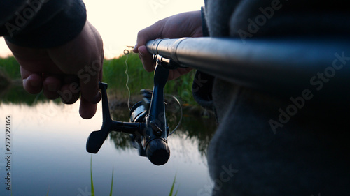 A man in the nature of fishing rests, throws the bait into the river, turns the coil and raise the bait to the top. Concept of: Fishing, Vacation, Holiday, Relax, River, Lake, Slow Motion, Clean Air.