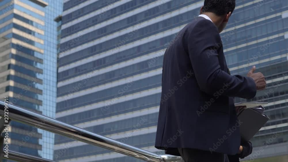 Young Indian businessman talking with businesswoman partner outdoors in city office building background Young Indian businessman talking with businesswoman partner outdoors in city office building background