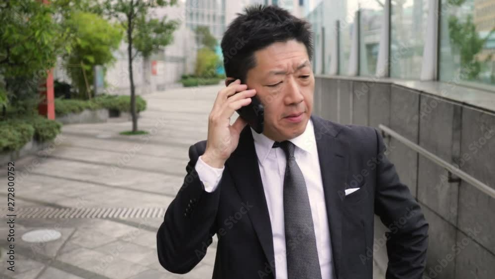 Japanese businessman talking on a cell phone. Japanese businessman talking on a cell phone.