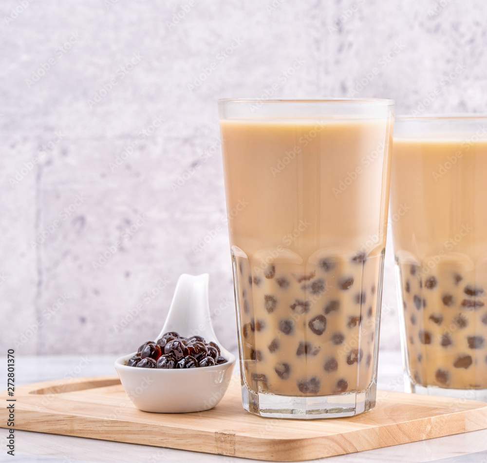 Popular Taiwan drink - Bubble milk tea with tapioca pearl ball in drinking glass on marble white table wooden tray background, close up, copy space Popular Taiwan drink - Bubble milk tea with tapioca pearl ball in drinking glass on marble white table wooden tray background, close up, copy space