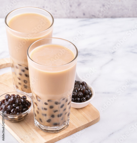 Popular Taiwan drink - Bubble milk tea with tapioca pearl ball in drinking glass on marble white table wooden tray background, close up, copy space