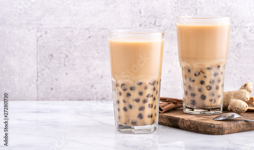 Popular Taiwan drink - Bubble milk tea with tapioca pearl ball in drinking glass on marble white table wooden tray background, close up, copy space