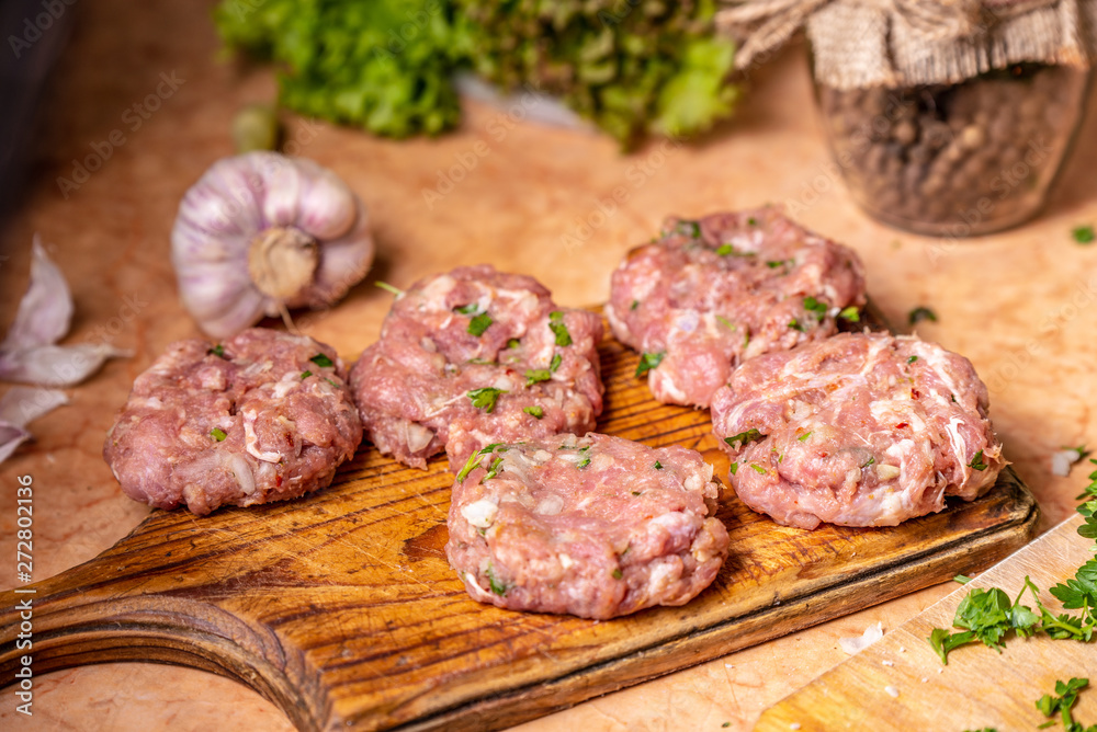 Five homemade raw patties on the board. Five homemade raw patties on the board.