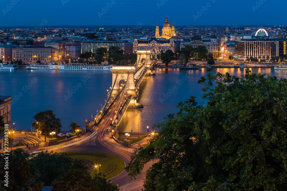 Obraz premium Budapest urban scape with the Basilica, Devil's Wheel and the illuminated Chain Bridge across the Danube River by night.