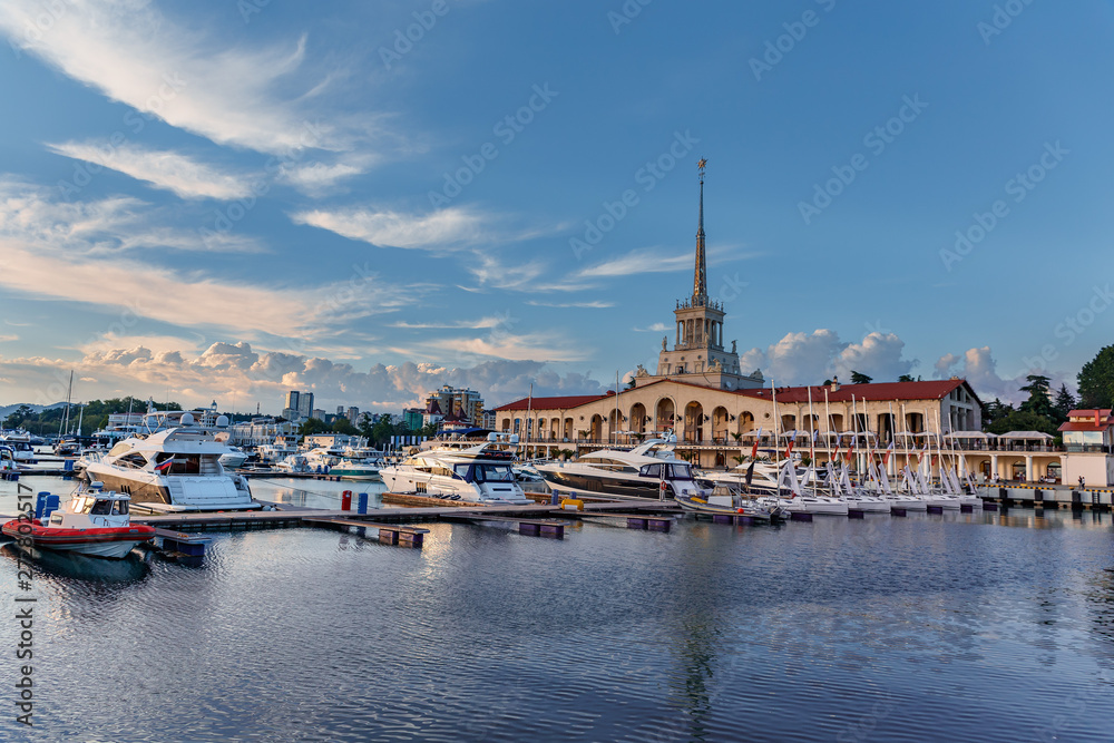 a small sailboat in the calm harbor of Sochi seaport against the background of the marine station