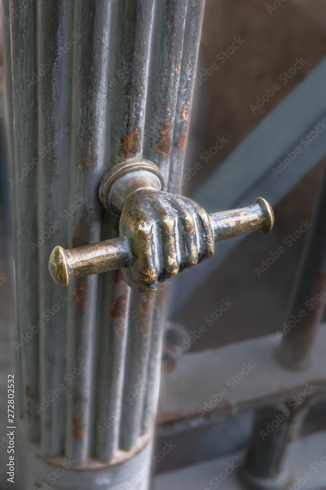 Old metal door handle in the shape of a hand on the door of the fence in a city park in St. Petersburg, Russia Old metal door handle in the shape of a hand on the door of the fence in a city park in St. Petersburg, Russia