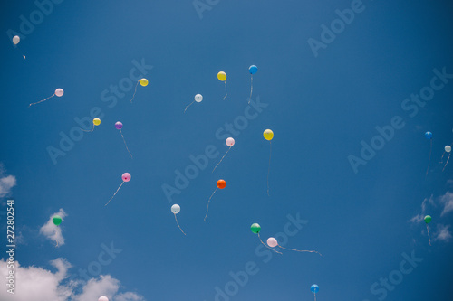 Multicolored balloons against the blue sky and clouds. Last call and graduation at school