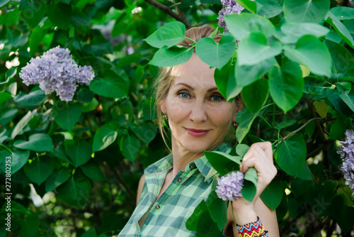 Woman in summer. Middle age blond woman in lilac. Portrait of a woman in a flowered garden. woman in summer. blooming garden