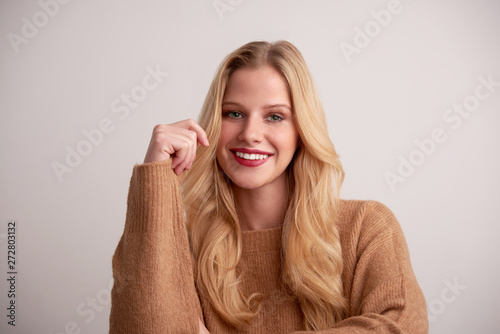 Cheerful young woman with blond hair and red lipstick sitting at isolated background © gzorgz