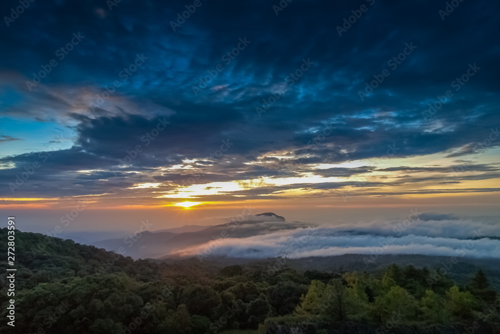 sunrise at Doi Inthanon, Km. 41 view point, mountain view misty morning on top hill around with sea of mist in valley and yellow sun light in the sky background, Chiang Mai, Thailand.