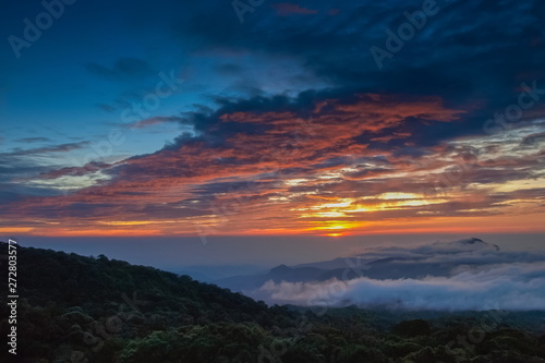sunrise at Doi Inthanon, Km. 41 view point, mountain view misty morning on top hill with sea of mist in valley and red sun light in the sky background, Chiang Mai, Thailand.
