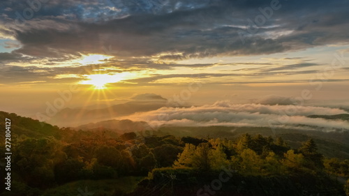 sunrise at Doi Inthanon, Km. 41 view point, mountain view misty morning on top hill panorama 180 degrees with sea of mist in valley and yellow sun light in the sky background, Chiang Mai, Thailand.