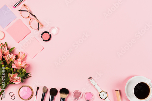 top view of cup of coffee, flowers, decorative cosmetics and accessories on pink