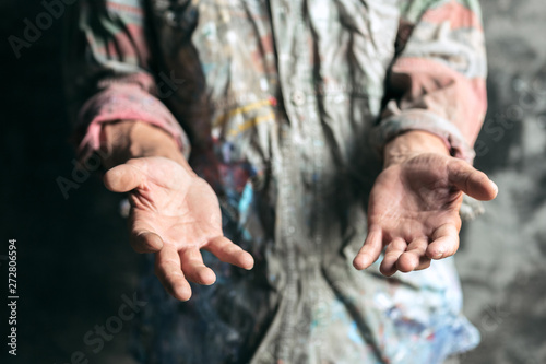 Foto Male beggar hands seeking money, coins from human kindness on the wooden floor at public path way or street walkway
